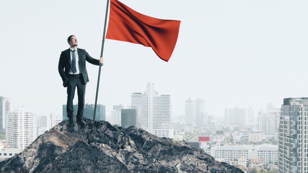 A business owner holds a red flag, helping show the red flags while hiring a marketing agency