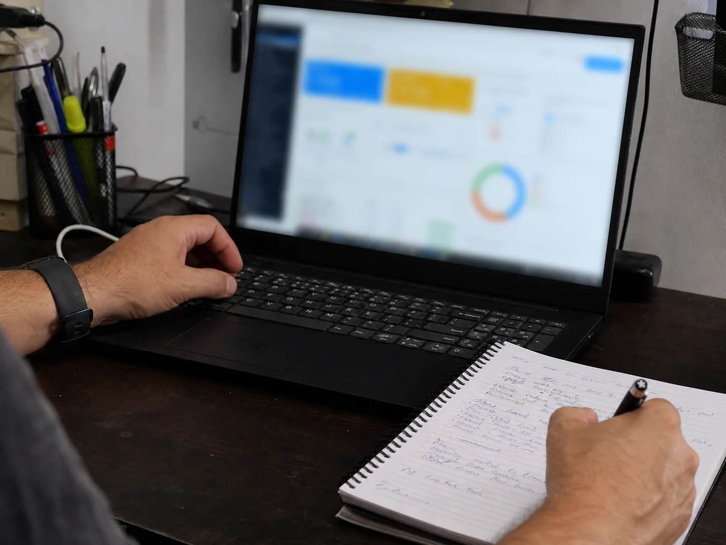 Business owner comparing website activity with a handwritten job notebook
