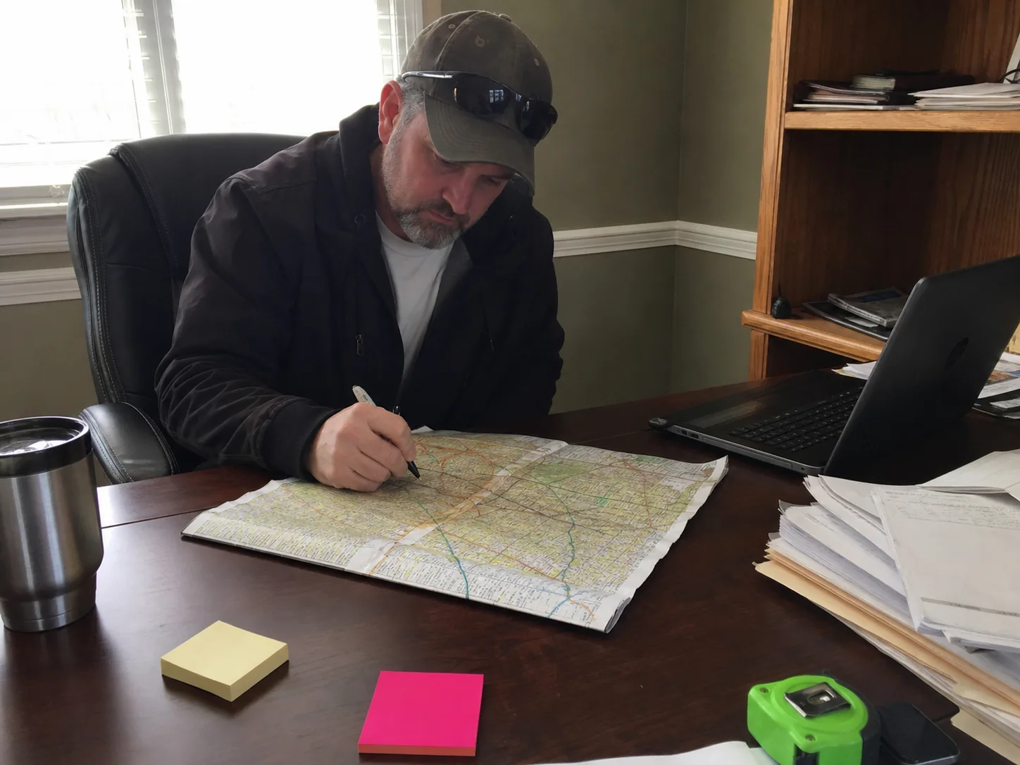 Local contractor planning service area pages with a paper map and laptop